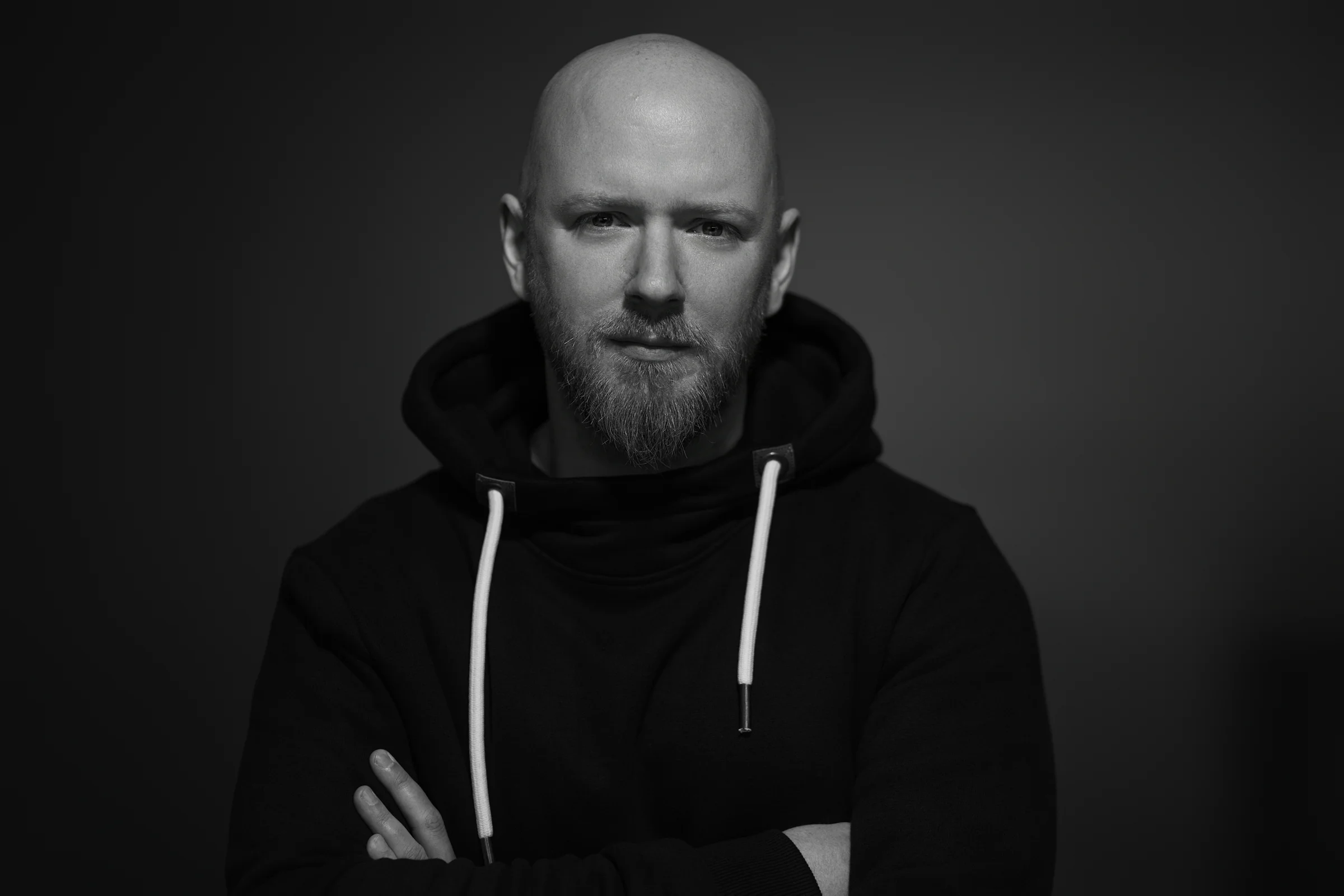 Constantin Melchers im schwarzen Hoodie, mit direktem Blick und verschränkten Armen, in Schwarz-Weiß