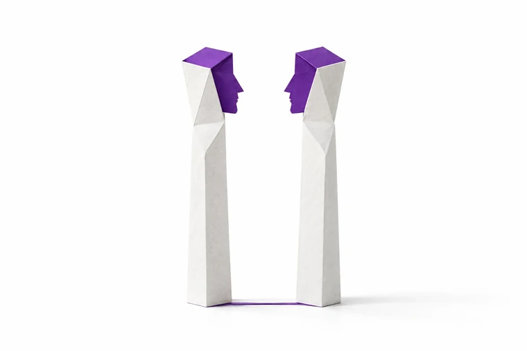 Zwei Hermen aus gefaltetem weißem Papier, die sich zuwenden. Ihre violetten Köpfe zeigen je ein Gesicht im Profil.